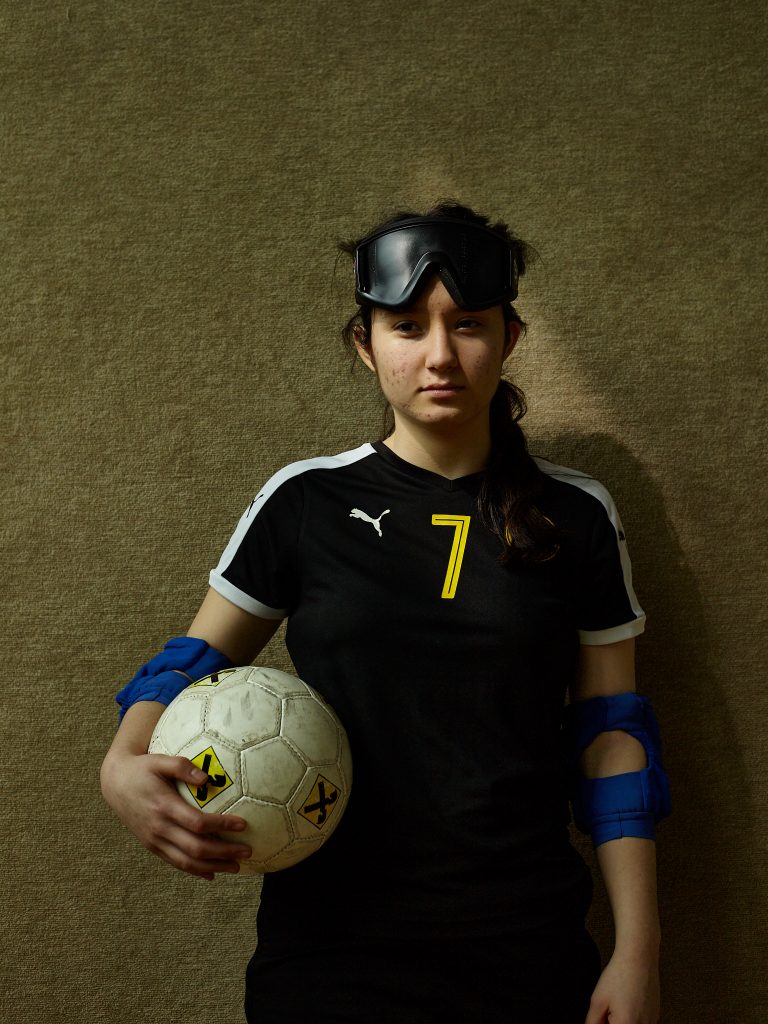 Portrait von Elif
| Blindensportlerin in der Turnhalle mit Ball.
aus: „In’s Schwarze“ in Tag
