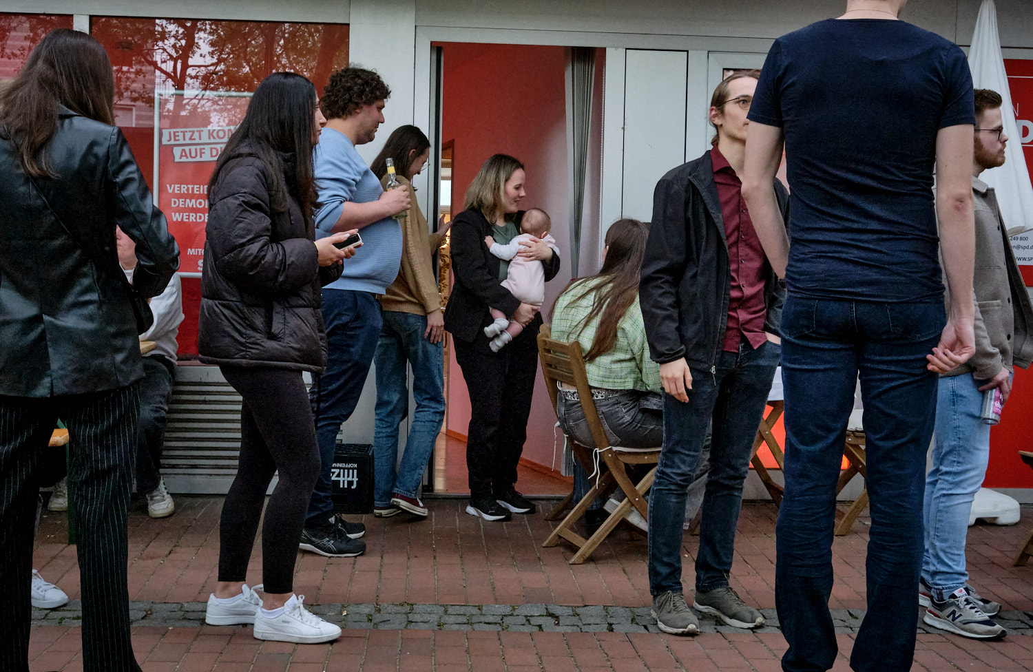 Jessica Rosenthal, Bundestagsabgeordnete der SPD, hält während einer Bürgersprechstunde mit Schülern aus Bonn ihre etwa acht Monate alte Tochter auf dem Arm. Für viele Abgeordnete ist es aufgrund des ständigen Reisens zwischen Bundestag und Wahlkreis sowie voller Terminpläne schwierig, genug Zeit für ihre Kinder zu haben. Am Abend brachte Jessica Rosenthals Mann ihre Tochter vorbei.

Jessica Rosenthal, a Member of the Bundestag (Germany’s federal parliament) for the SPD (Social Democratic Party), holds her approximately eight-month-old daughter in her arms during a citizen consultation with students from Bonn. For many parliamentarians, the constant travel between the Bundestag and their constituency, along with busy schedules, makes it difficult to spend enough time with their children. In the evening, Jessica Rosenthal’s husband brought their daughter to her.