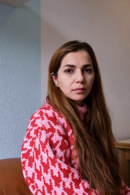 Portrait von Shoreh Faridiin ihrer Wohnung in Essen. Shoreh gehört zur iranischen Diaspora in Deutschland. Aufgenommen am 09.12.2022 in Essen. 

Shoreh Faridi wurde vor 31 Jahren in Karadj, einer Nachbarstadt Teheran's geboren.  
2021 kam sie nach Deutschland um ihren Doktor in Elektrochemie an der Universität Essen-Duisburg zu machen. Zuvor hatte sie im Iran ein Physikstudium abgeschlossen.
Als Teenager besuchte sie dasselbe Hochbegabtengymnasium wie Sarina Esmailzadeh, einer 16-jährigen Schülerin, die durch Milizen des Regimes zu Tode geprügelt wurde. 
Wenn sie auf Instagram Videos anschaut wie Sarina das Lied "Take me to church" von Hozier singt, welches auch ihr Lieblingslied ist, oder über Frauenrechte redet, dann sieht sie ihr jüngeres Ich, sagt sie. Es sind dieselben Gespräche, dieselben Themen wie damals, Sarina könnte auch sie sein. Es sei nur schwer zu akzeptieren, dass sie lebe, und Sarina 
Tod ist sei.

Zitat:"Als Frau bist du im Iran Bürger zweiter Klasse. Mein Mutter hatte vor der Revolution 1979 mehr Freiheiten als ich jetzt. Noch vor einiger Zeit war es mir peinlich, dass viel Iraner:innen sich einfach still unterdrücken liessen. Aber jetzt bin ich froh, dass diese Revolution von Frauen ausgeht, dass sie ihre Rechte einfordern, dass sie sich nicht mehr unterdrücken lassen wollen, dass sie aufgewacht sind. Ich will nicht zu optimistisch sein, aber ich glaube der nächsten iranischen Regierung wird eine Frau vorstehen."