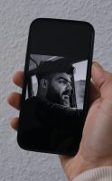 Aufsicht auf ein Portrait des Rappers Yasin auf dem Bildschirm eines Smartphones gehalten von Parham Mehrdad Farhadi. Aufgenommen am 20.12.2022 in Dortmund.

Saman Yasin ist ein bekannter kurdischer Rapper, der das iranische Regime in seinen Texten und auf Social Media immer wieder lautstark kritisiert hat. Seit zwei Monaten ist er inhaftiert und von Hinrichtung bedroht. Yasin kommt, wie Parham, aus Kermansha und gehört ebenso zur religiösen Minderheit der Yarsan. Deshalb ist er für Parham zur Identifikationsfigur geworden. Er kann sehr gut nachfühlen, was Yasin in seine Texten sagt.